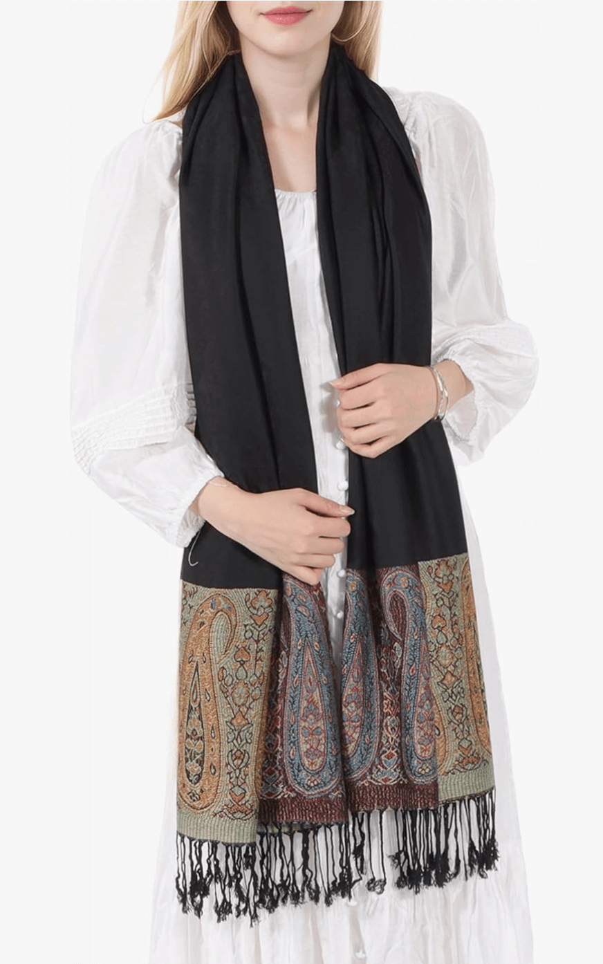 Woman wearing a black luxury pashmina scarf with intricate paisley patterns and fringes.