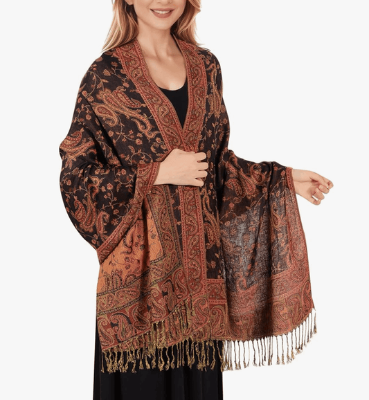 Elegant woman modeling a luxurious black and orange festival pashmina with intricate patterns and fringes.
