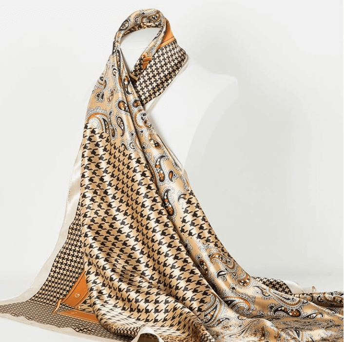 Elegant gold and black patterned satin headscarf draped elegantly over a mannequin.
