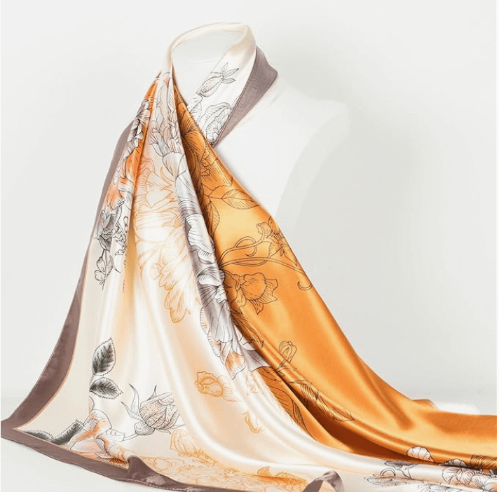 Veloura Satin Headscarf featuring floral patterns in orange, cream, and grey, draped elegantly on a mannequin.