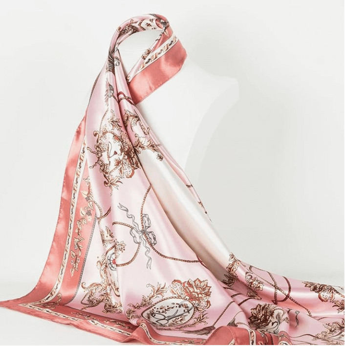 Veloura Satin Headscarf elegantly draped over a mannequin, showcasing its luxurious pink design and intricate patterns.