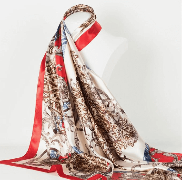 Veloura Satin Headscarf draped elegantly on a mannequin, featuring a vibrant floral and paisley design in cream and red.