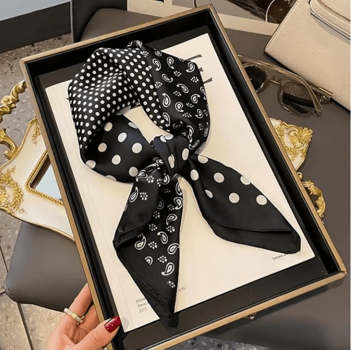 Vintage Luxe Satin Scarf in black with polka dot patterns, displayed on a magazine in a stylish tray.