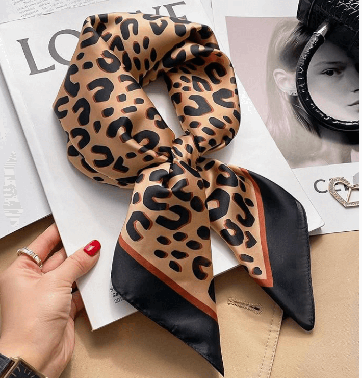 Vintage luxe satin scarf featuring a chic leopard print design laid on a fashion magazine.